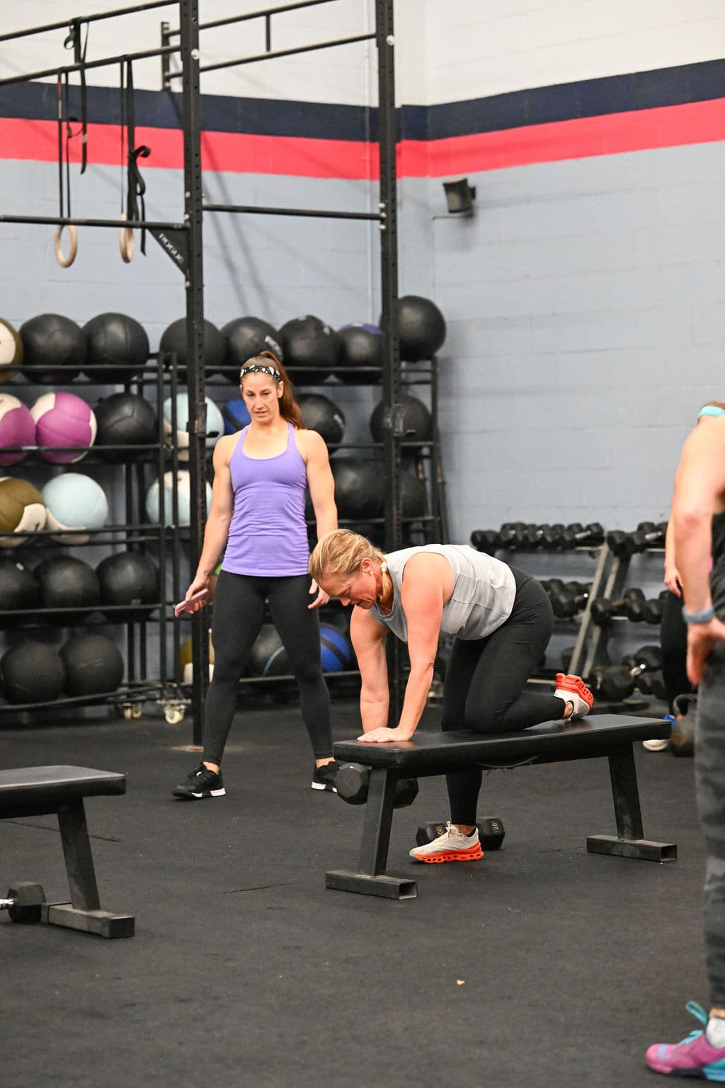 A Monument Fitness coach guiding a member through a dumbbell row