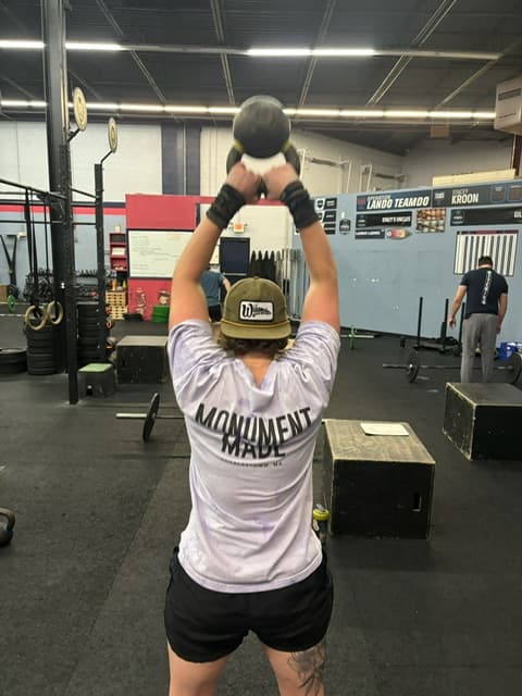 Members swinging kettlebells together in class